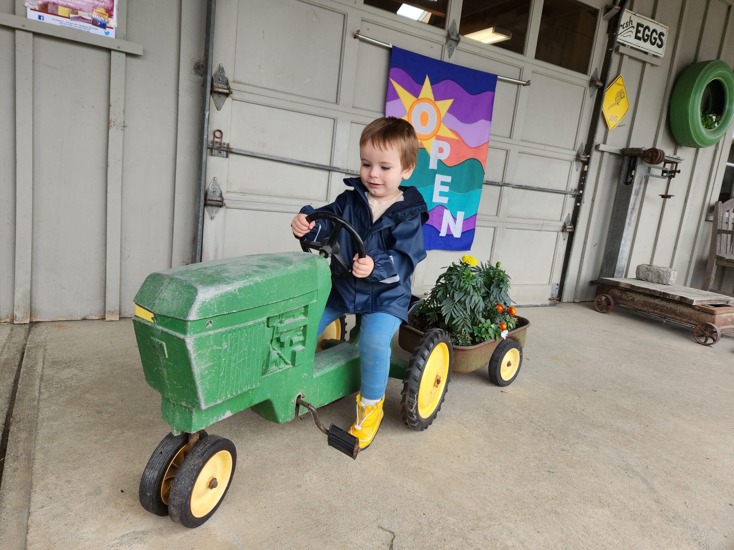 Child sitting on a green toy tractor.